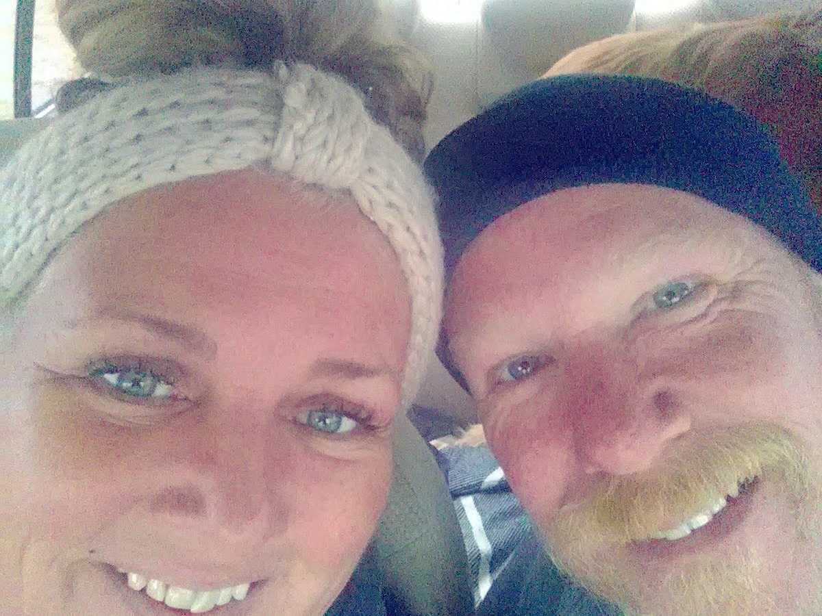 Wife smiles in car beside husband with cancer
