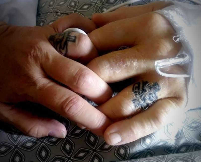 Close up of husband with cancer and wife holding hands who have matching tattoos on their fingers