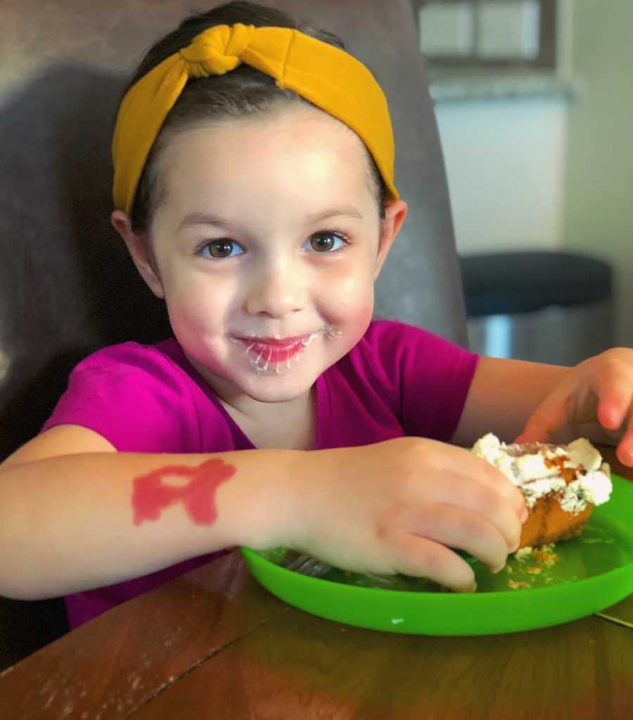 Little girl with autism smiles as she sits at table eating