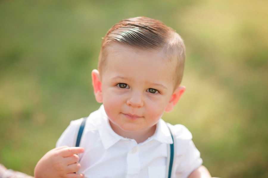 Little boy with autism stands outside with hair slicked to the side
