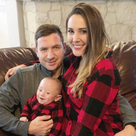 Woman sits on couch beside newborn and father of her baby