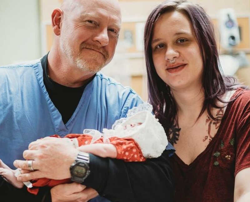 Woman smiles beside man who holds newborn that will soon die