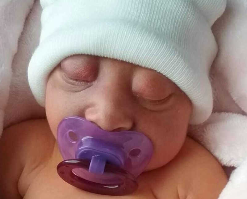 Sleeping newborn with hat on and pacifier in her mouth who wasn't suppose to survive