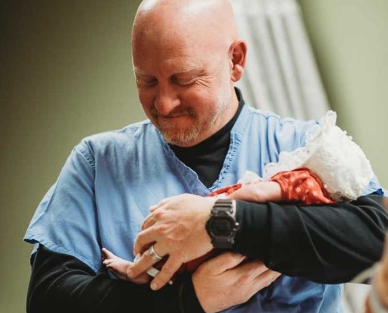 Doctor smiles as he holds newborn that will soon pass away