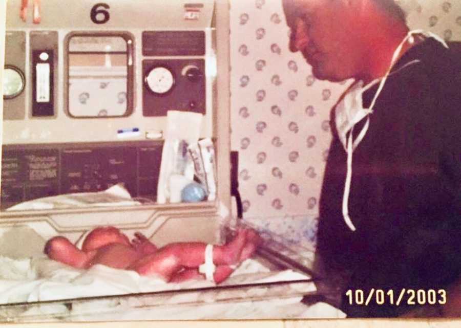 Father stands over baby in NICU