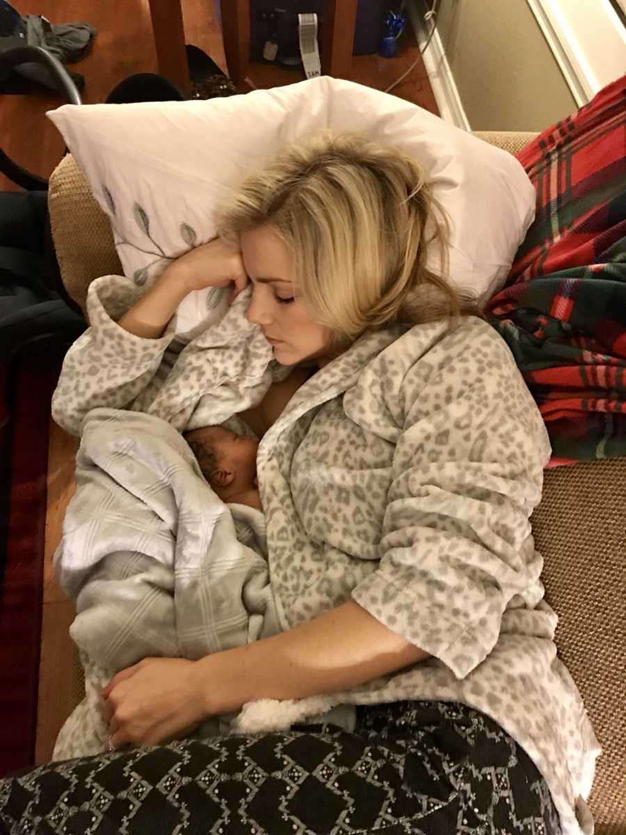 Mother lays asleep on couch with adopted son in her arms