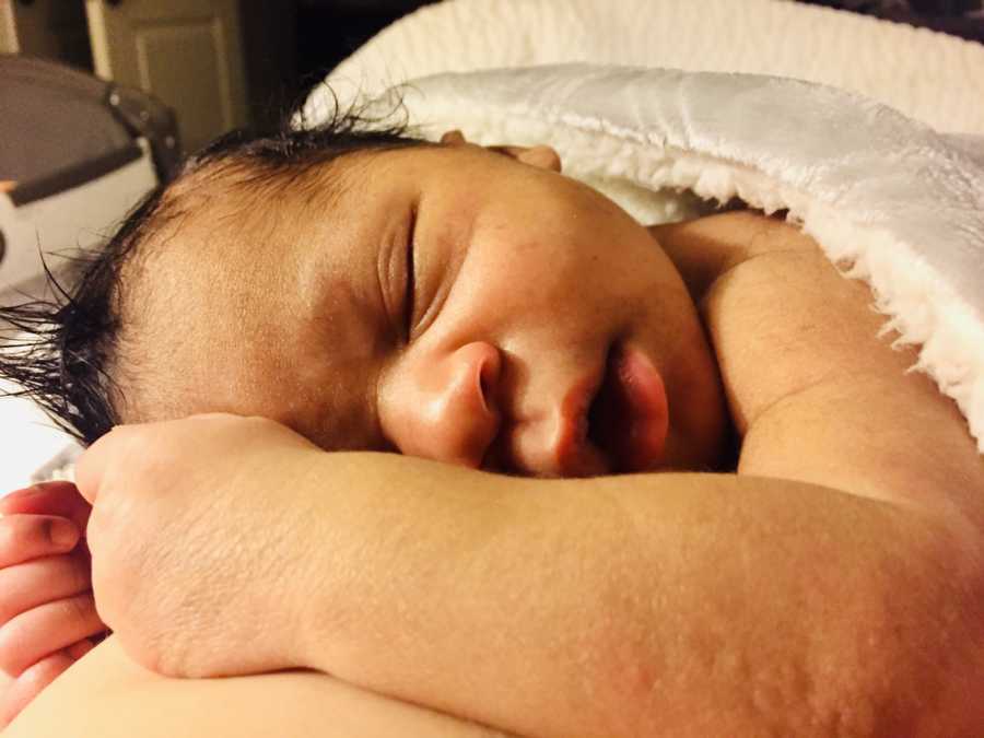 Close up of newborn who was adopted sleeping on his stomach