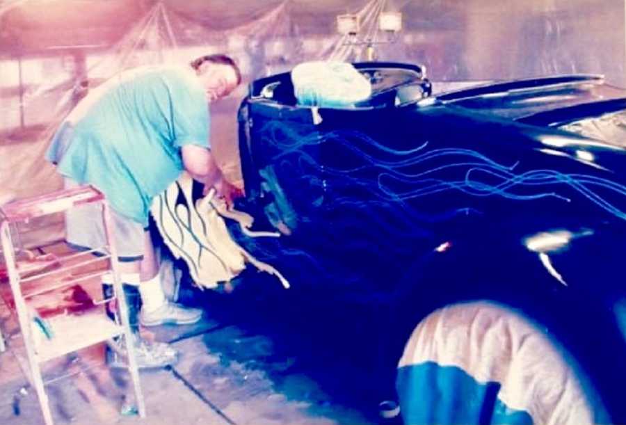 Man stands in garage tending to car