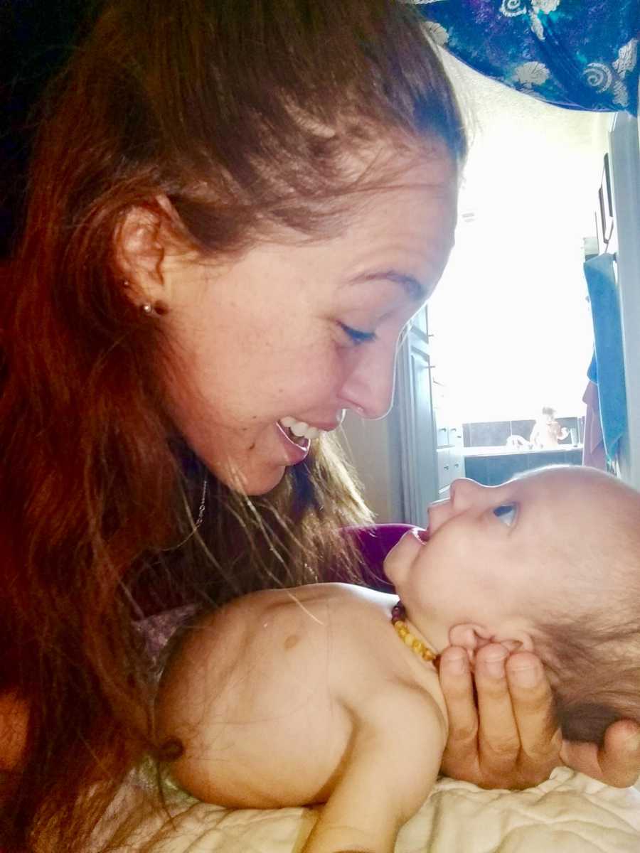 Mother smiles down at baby son with pace maker in her arms