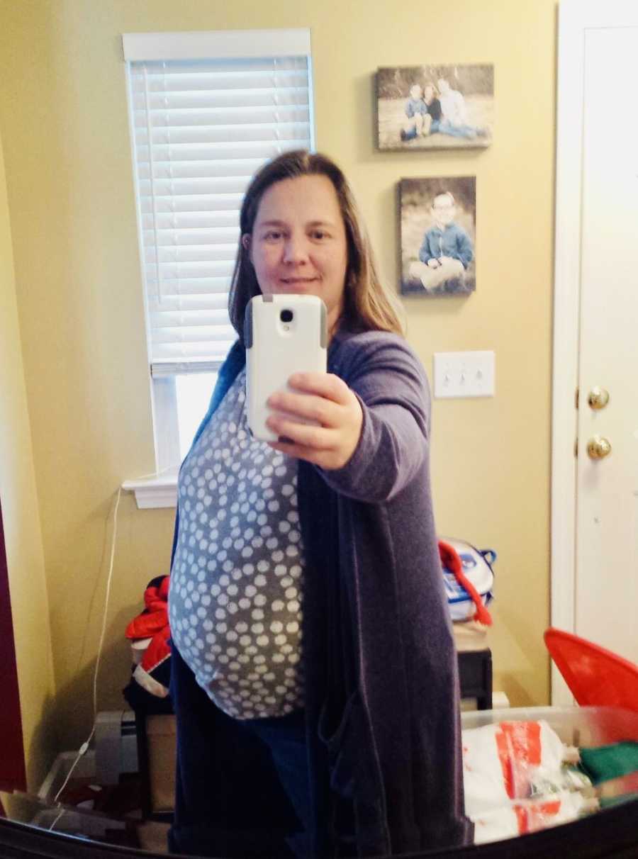 Woman who became pregnant through IVF stands smiling in mirror selfie in her home