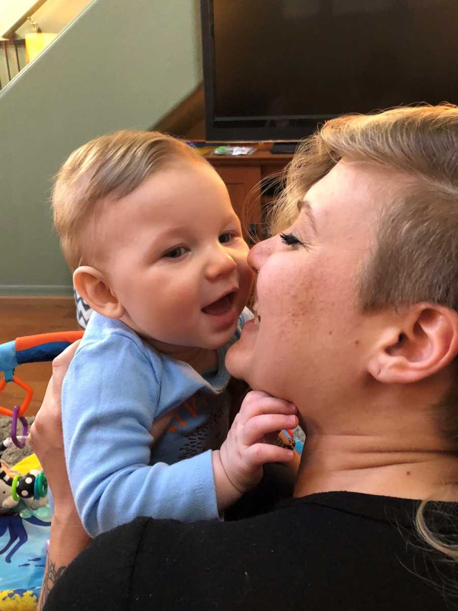 Single mother smiles as she holds baby boy close to her face