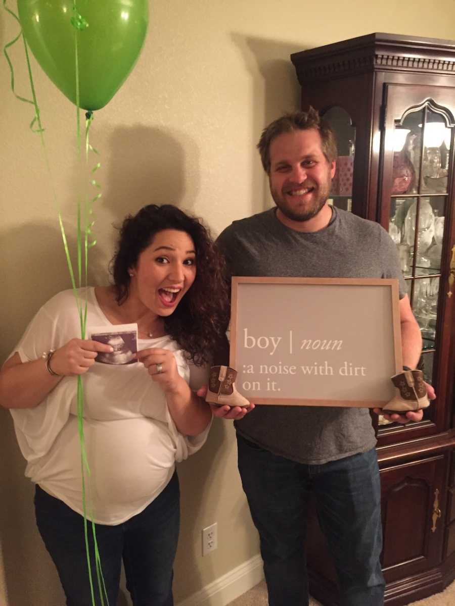 Husband stands smiling beside pregnant wife who holds ultrasound picture of baby and balloons