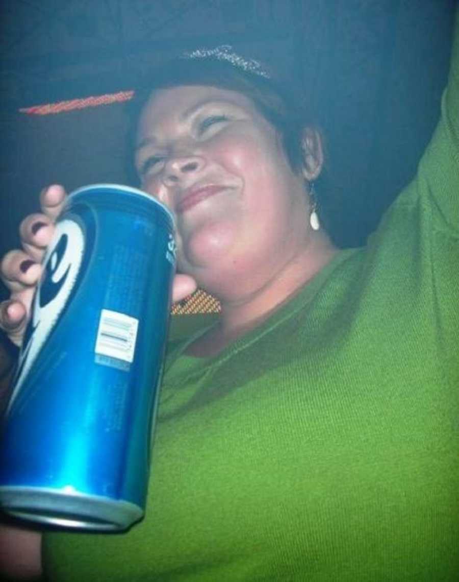Alcoholic woman smiles as she holds tall can of beer