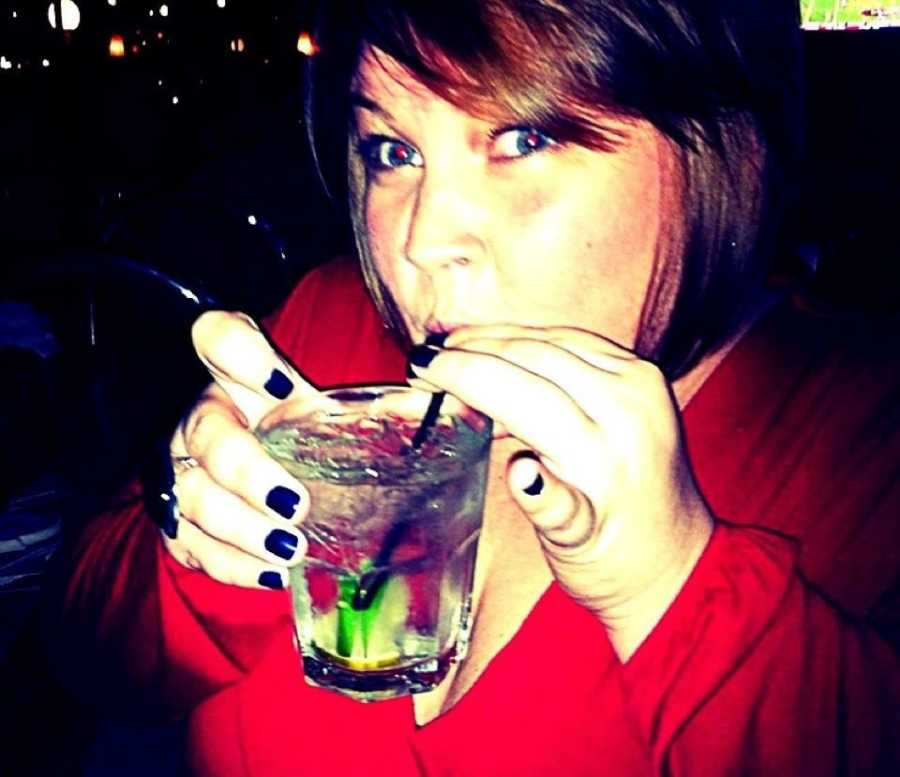 Alcoholic woman sips from straw of her drink