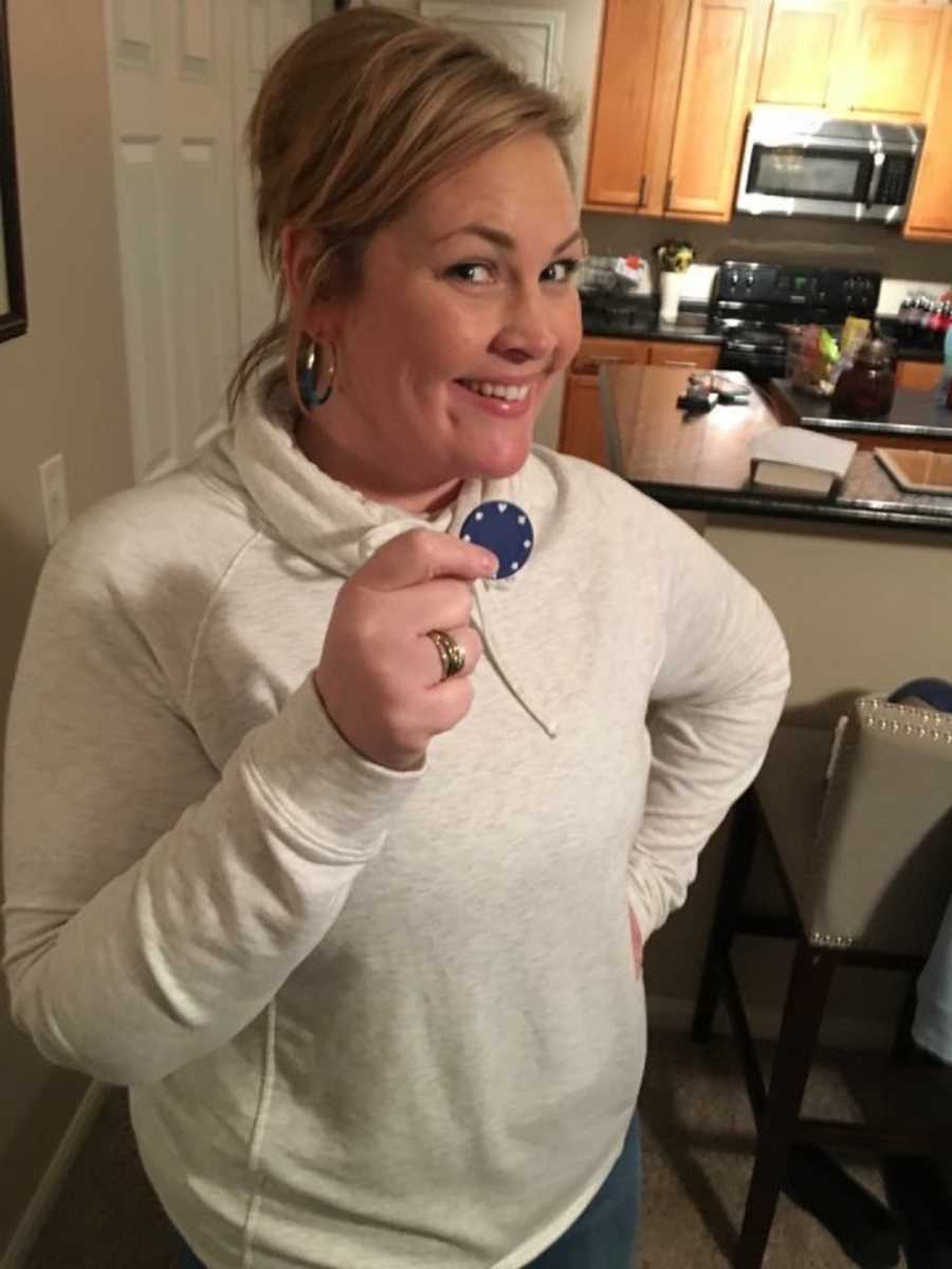 Woman smiles in home holding sobriety chip