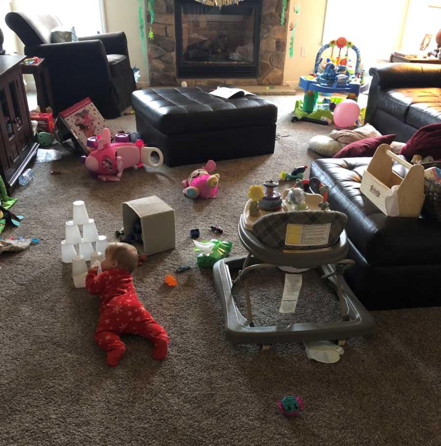 Baby lays on stomach on floor of home in room that is covered in toys