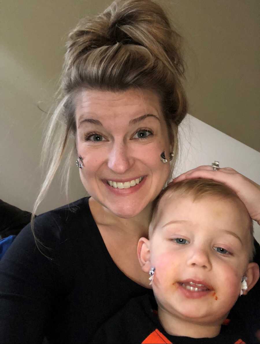 Mother who has stickers on her face smiles in selfie with son who also has stickers on his face