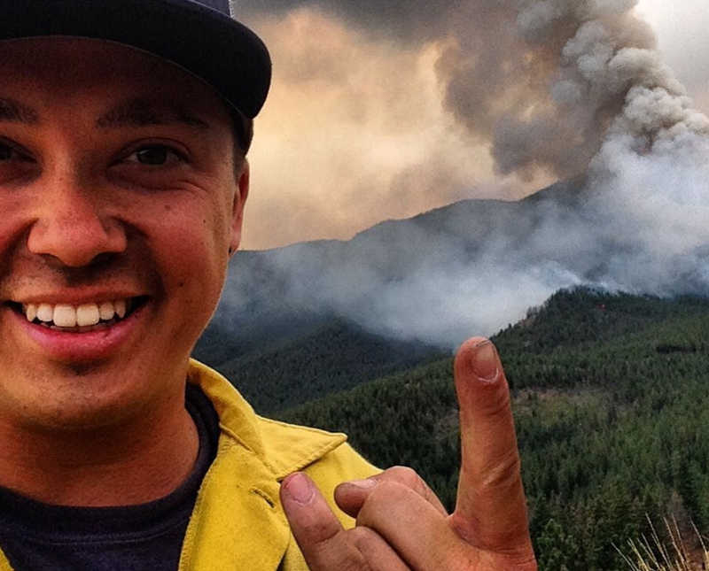 Man who works for US forest service smiles in selfie while pointing to smoke in background