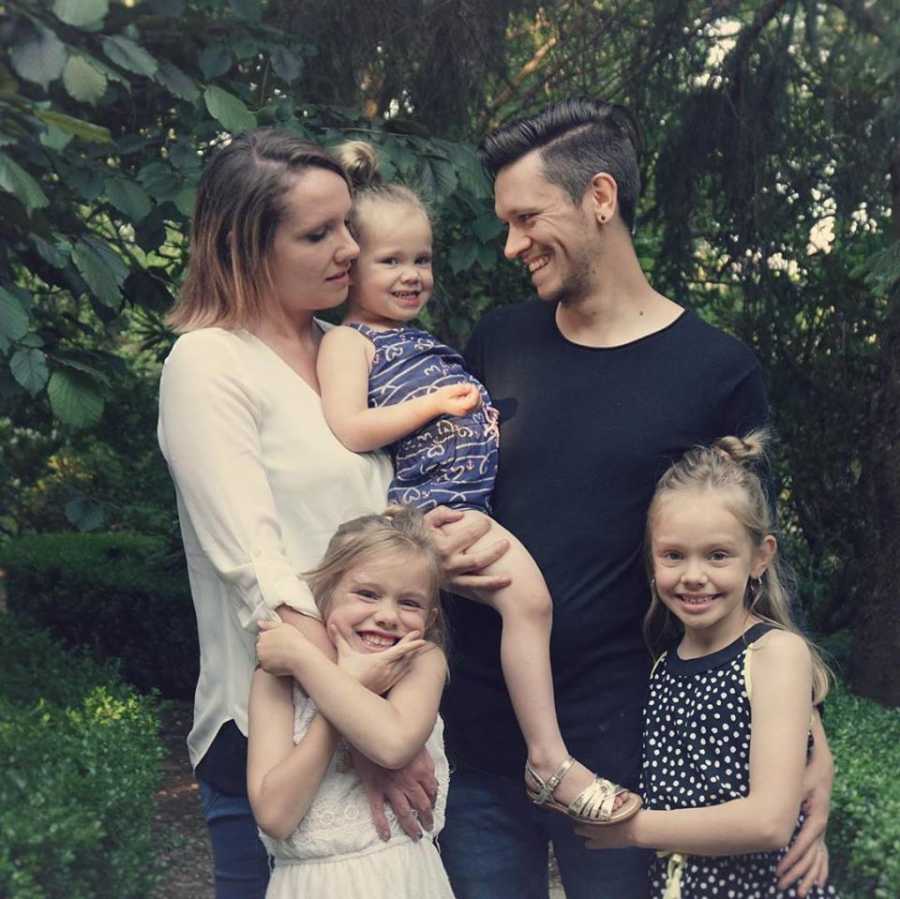 Mother who had hysterectomy stands holding daughter beside husband along with two other daughters