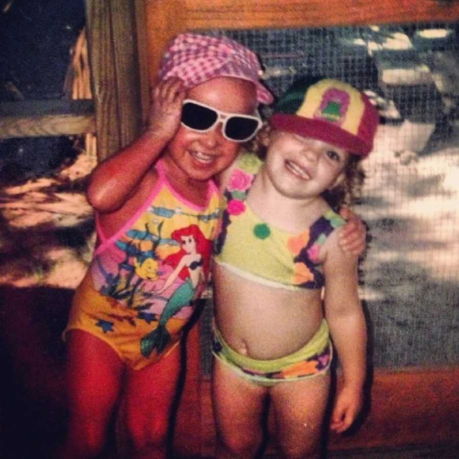 Little girl with Ichthyosis stands in swimsuit and sunglasses with arm around another little girl