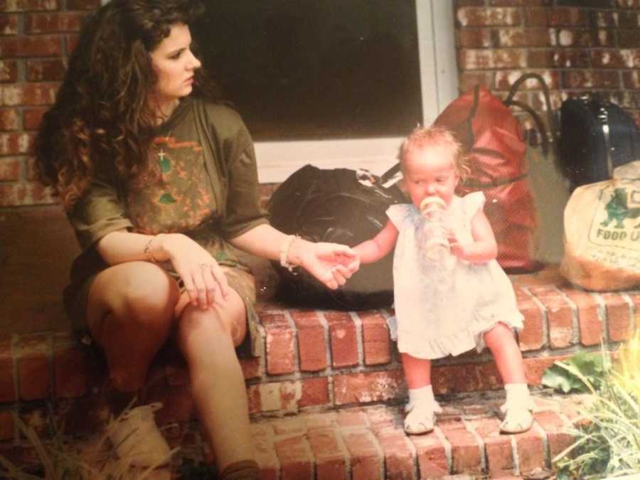 Mother sits on front steps of home holding hands with baby who has Ichthyosis