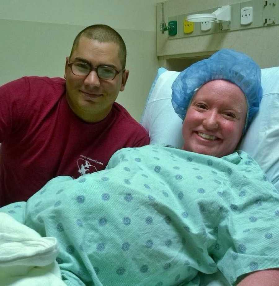 Pregnant woman with Ichthyosis lays in hospital bed with hair net on as husband lays beside her