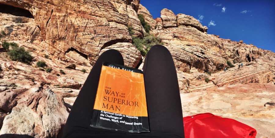 Book resting on woman's legs with cliffs in background