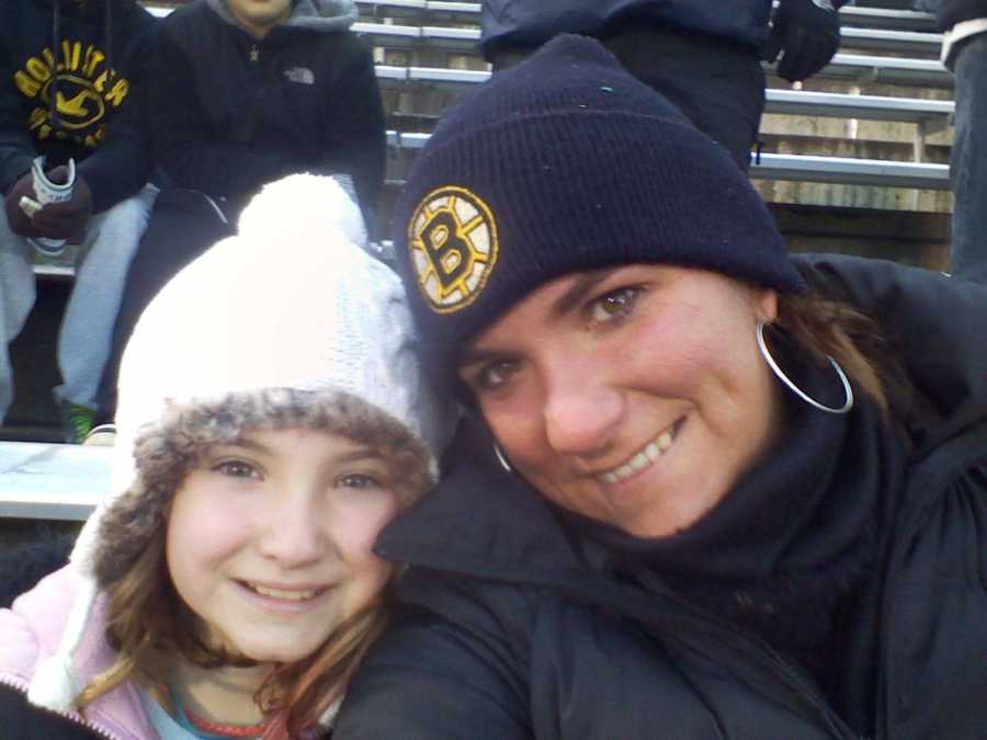 Mother smiles in selfie with her young daughter as they sit in bleachers