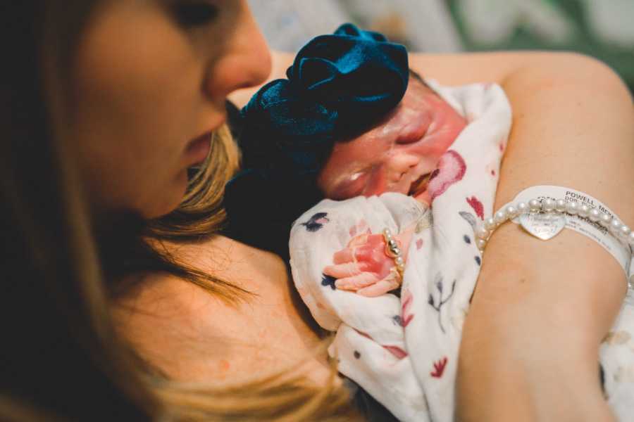 Close up of newborn with heart defect asleep in mother's arms