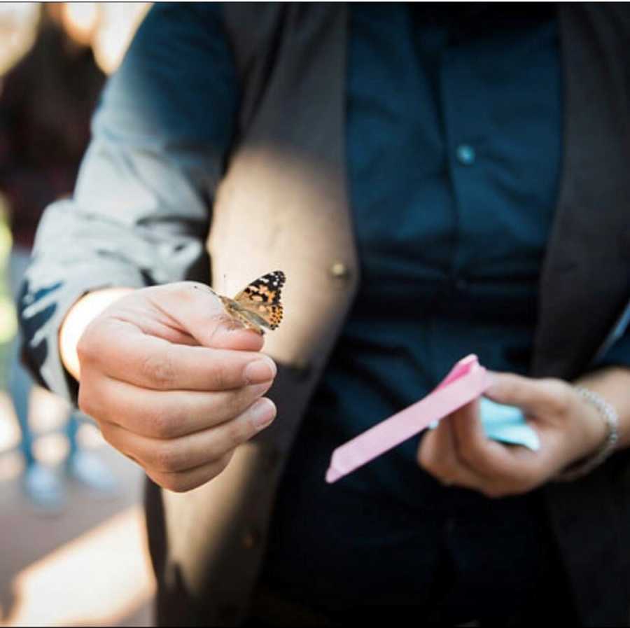 Butterfly rests on woman's finger who lost three babies