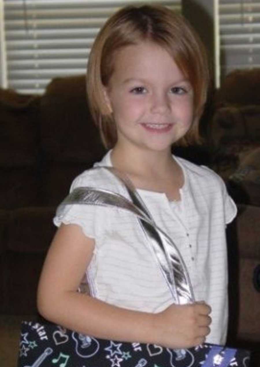Little girl smiles in home with purse on her shoulder