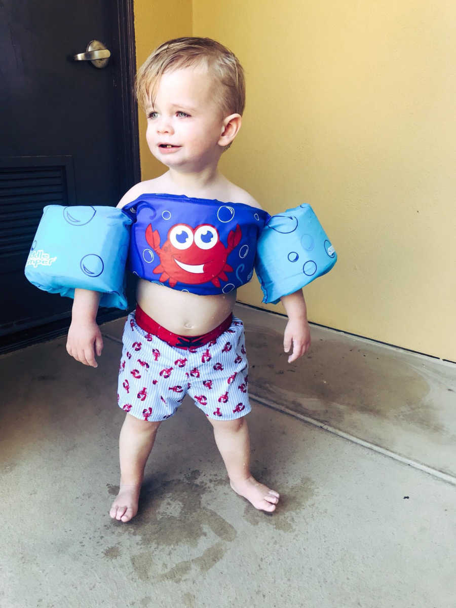 Little boy stands in bathing suit and swim floaties whose aunt and uncle love spending time with