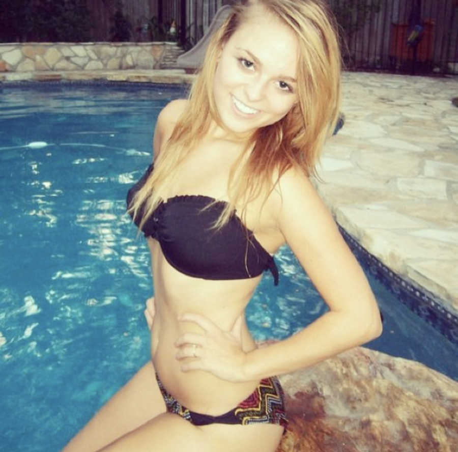 Young woman with gastroparesis stands smiling in pool with hands on her hips