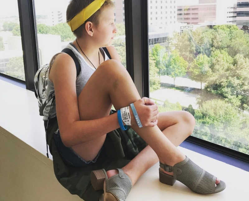 Girl with leukemia sits in hospital looking out window