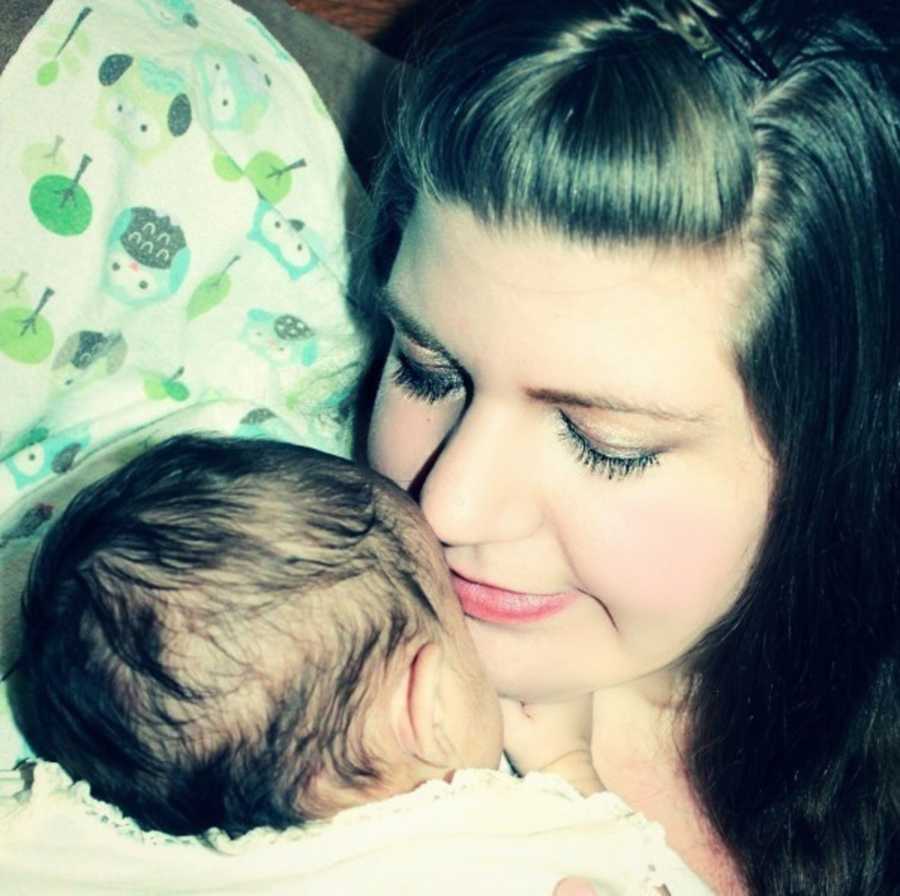 Mother closes her eyes as holds newborn to her chest