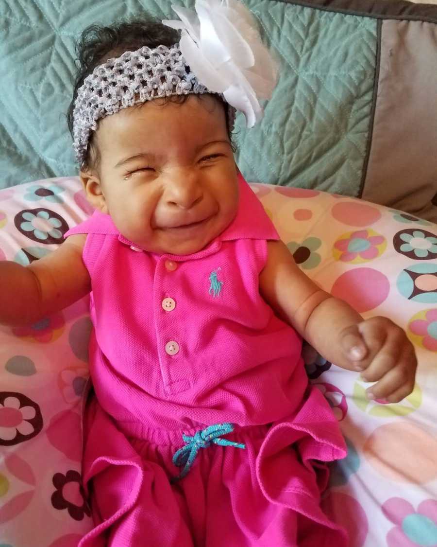 Baby girl with anophthalmia sits in bean bag chair smiling