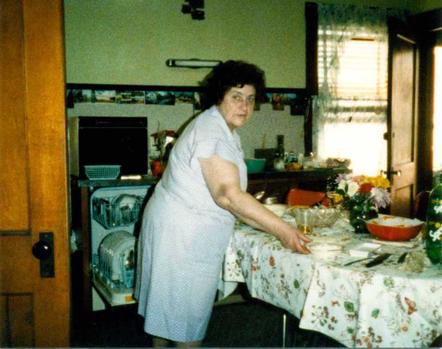 Woman looks over her shoulder as she stands in home clearing a table