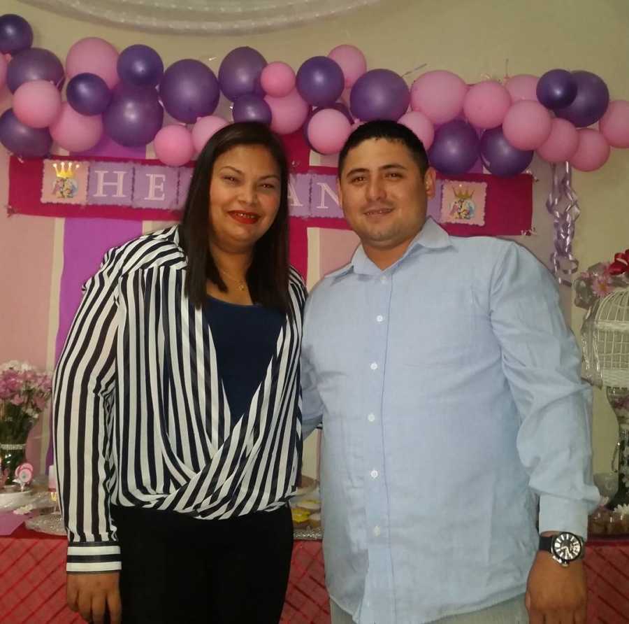 Husband and wife stands smiling at their baby shower