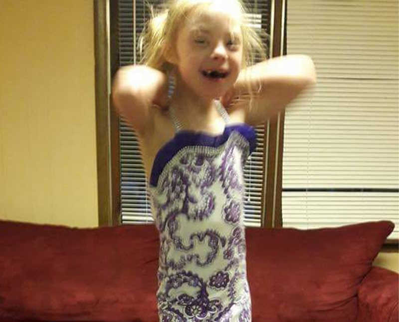 Little girl with down syndrome smiles as she put on purple rhinestone outfit