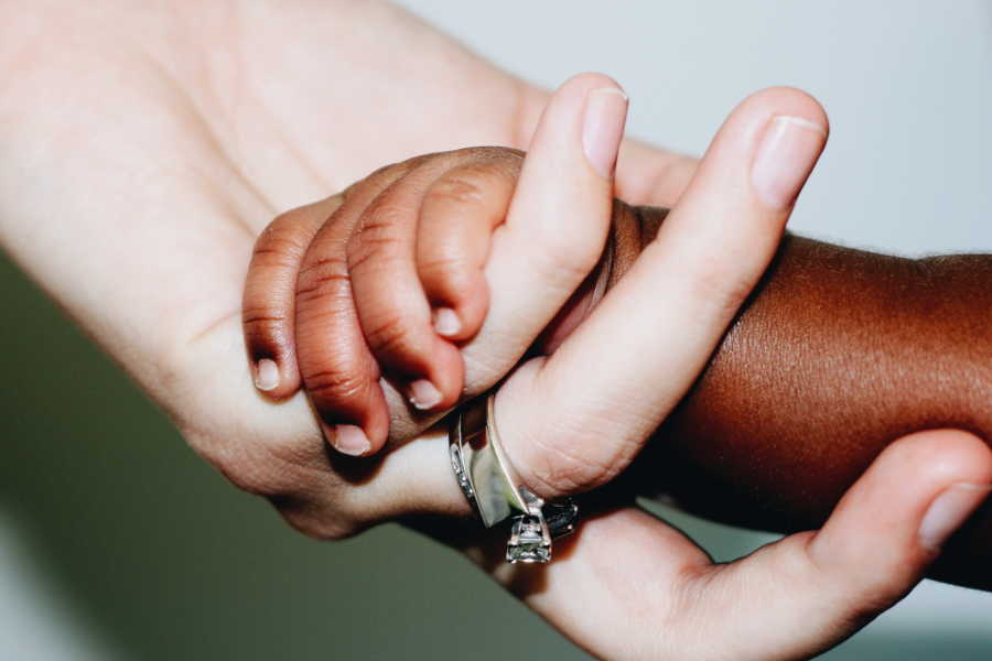 Close up of mother and adopted son holding hands