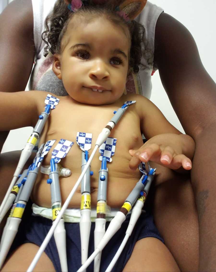 Little girl sits in mothers lap with wires attached to her chest