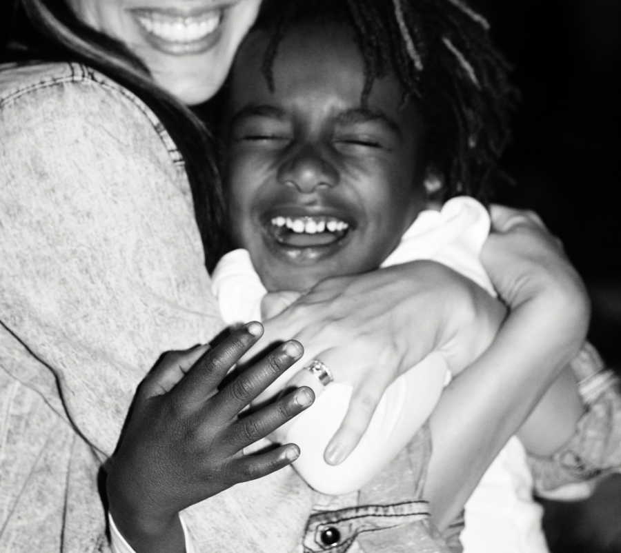 African American adopted boy smiles as he hugs his mother