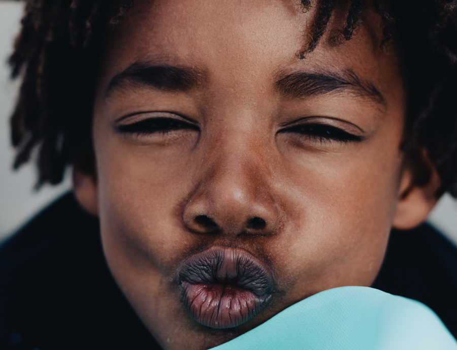 African American boy who has white parents pushes his lips out while his eyes are closed