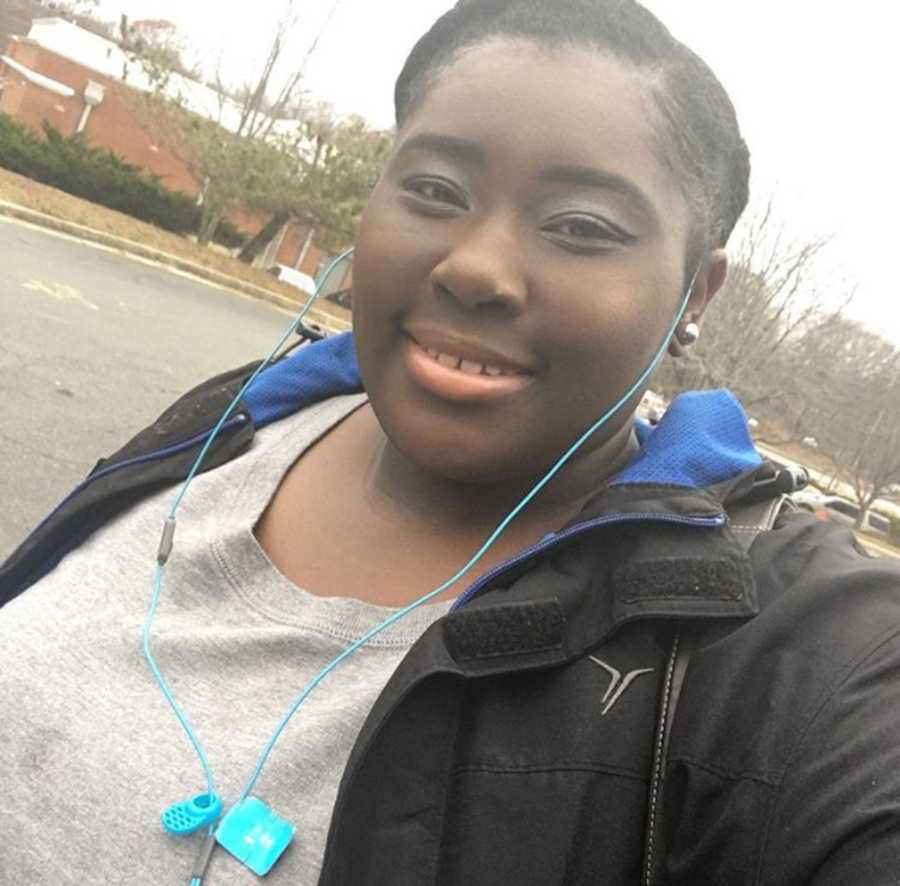 Woman who was raped by uncle as a little girl smiles as she walks outside with headphones in