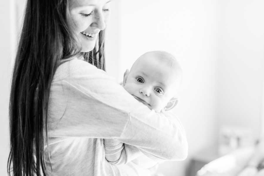 Mother smiles as she holds baby in her arms