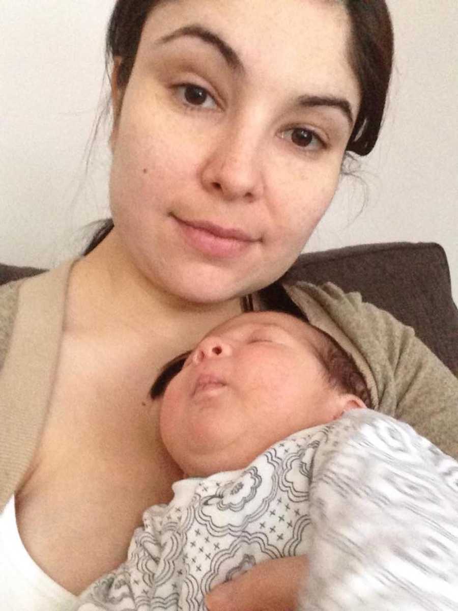 Mother who says new mothers don't often shower smiling in selfie while newborn sleeps on her chest