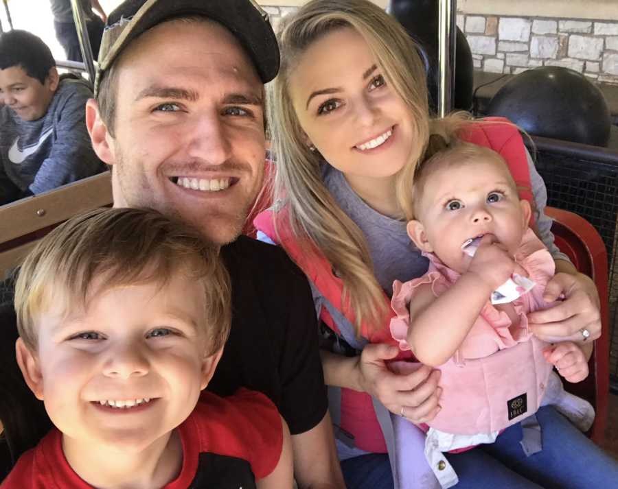 Husband and wife with gastroparesis sits on bench with their two young kids on their lap