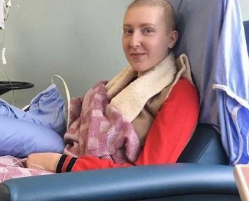 Young woman with Hodgkin's lymphoma smiles in hospital chair