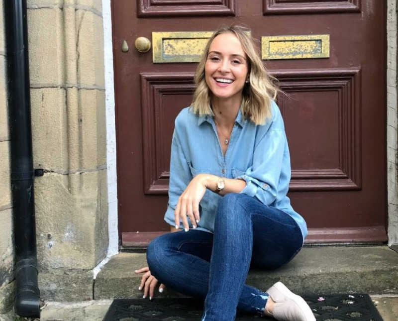 Woman who face domestic abuse sits on step of front door smiling