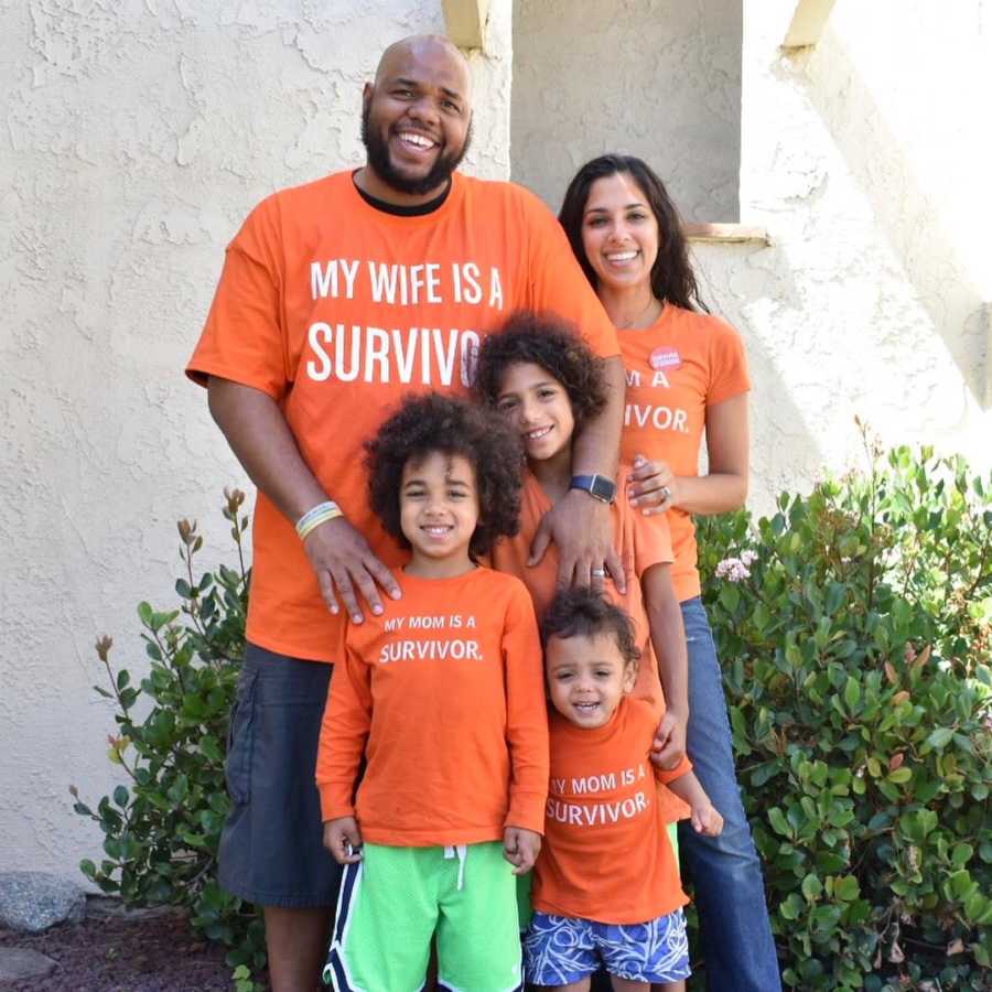 Woman who survived shooting stands outside smiling with her husband and three children